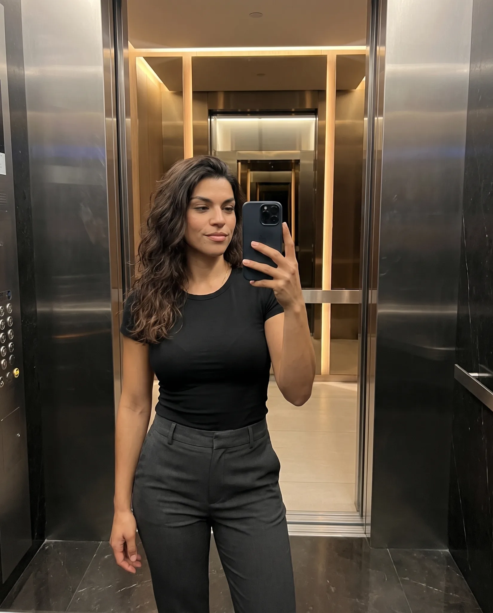 Lucia taking a mirror selfie in a contemporary elevator